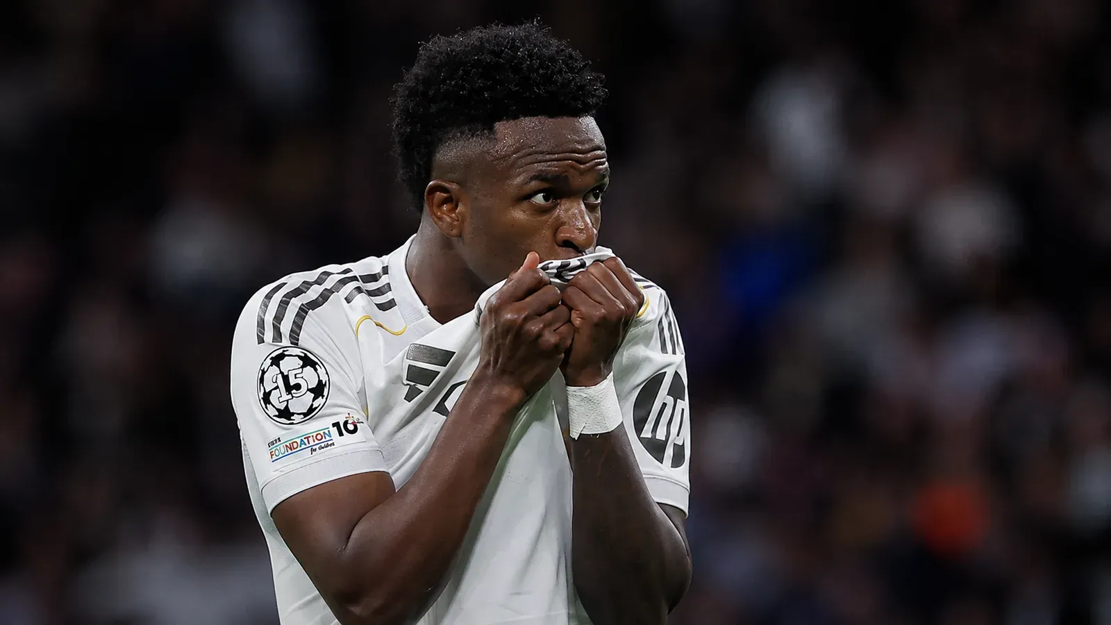 Vinícius Jr. besa la camiseta blanca con ambas manos durante un partido.